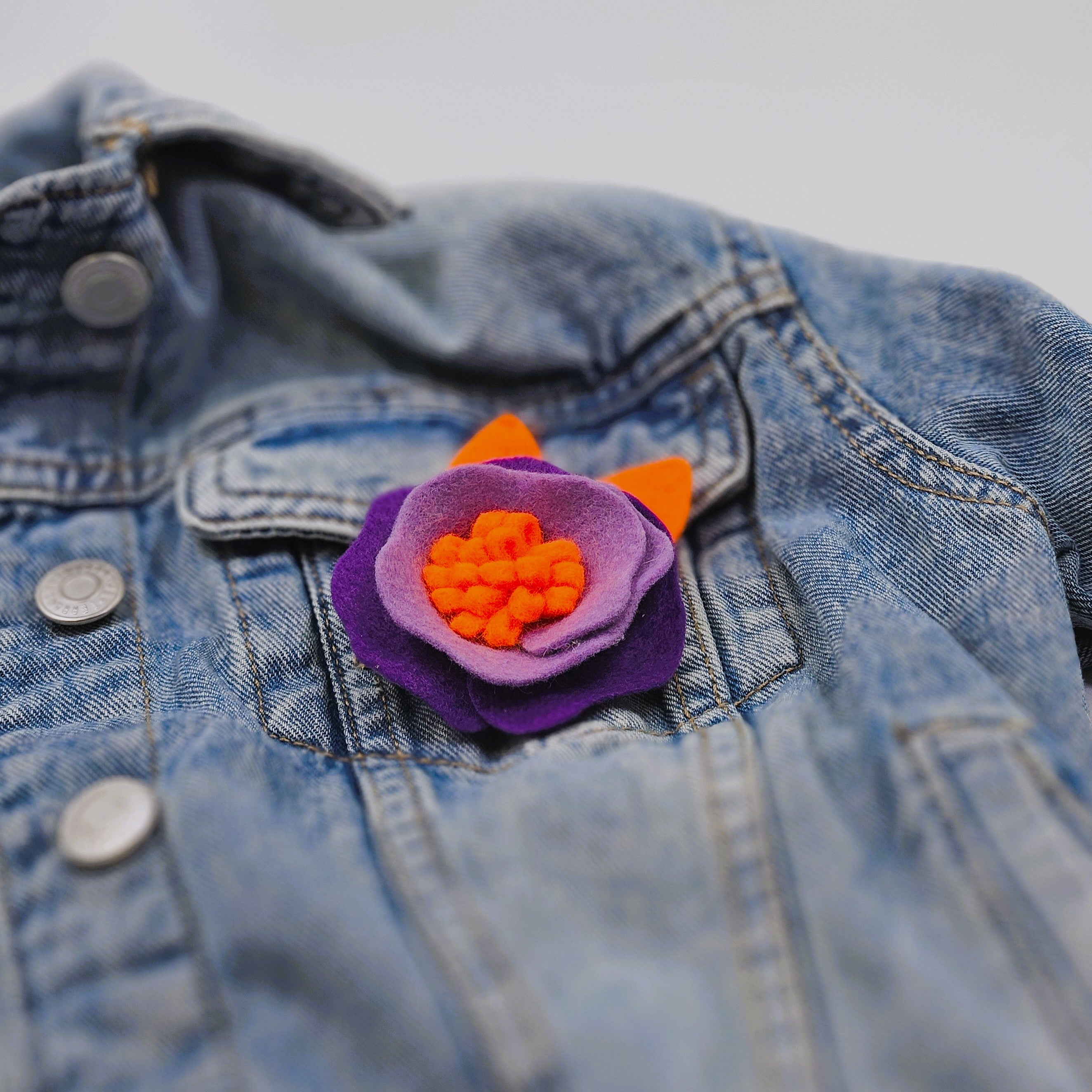 Елегантна брошка цвете в артистично светло, тъмно лилаво и ярко оранжево